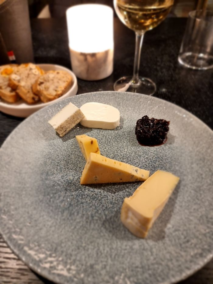 A gourmet cheese platter featuring assorted cheeses, cranberry jam, and wine pairing, perfect for food photography.