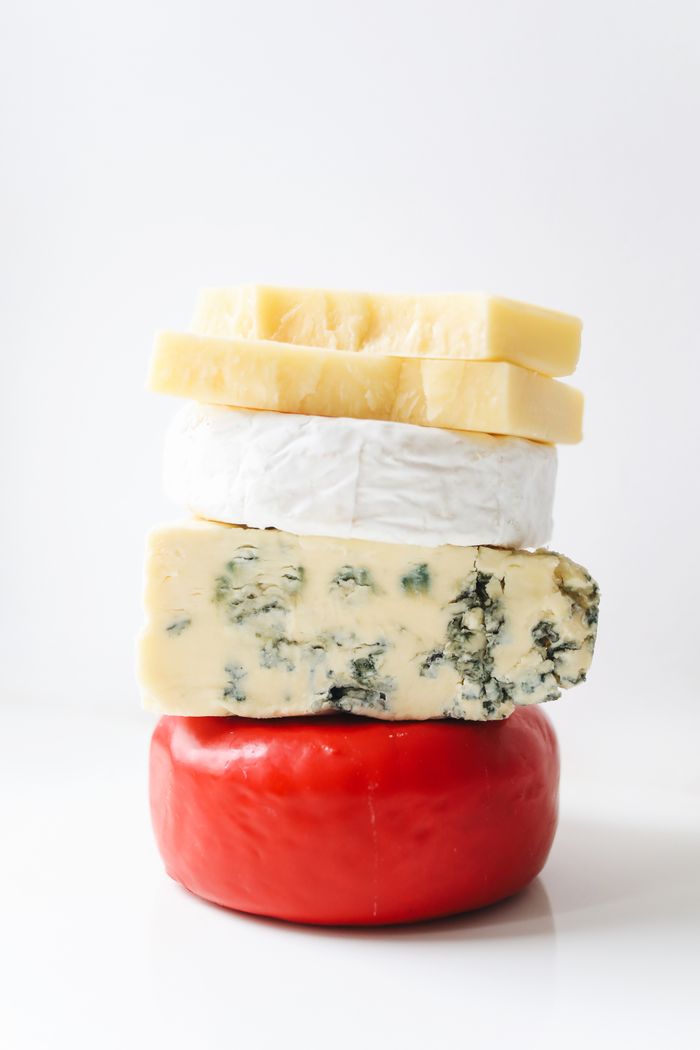 Artistic stack of diverse gourmet cheeses on a white background.
