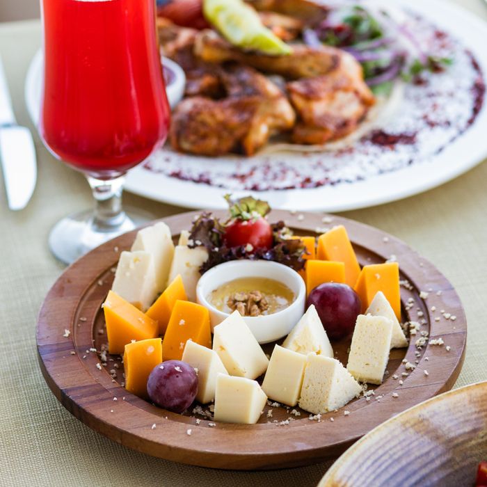 A vibrant platter of assorted cheeses and grapes, paired with a refreshing red drink for an elegant dining experience.